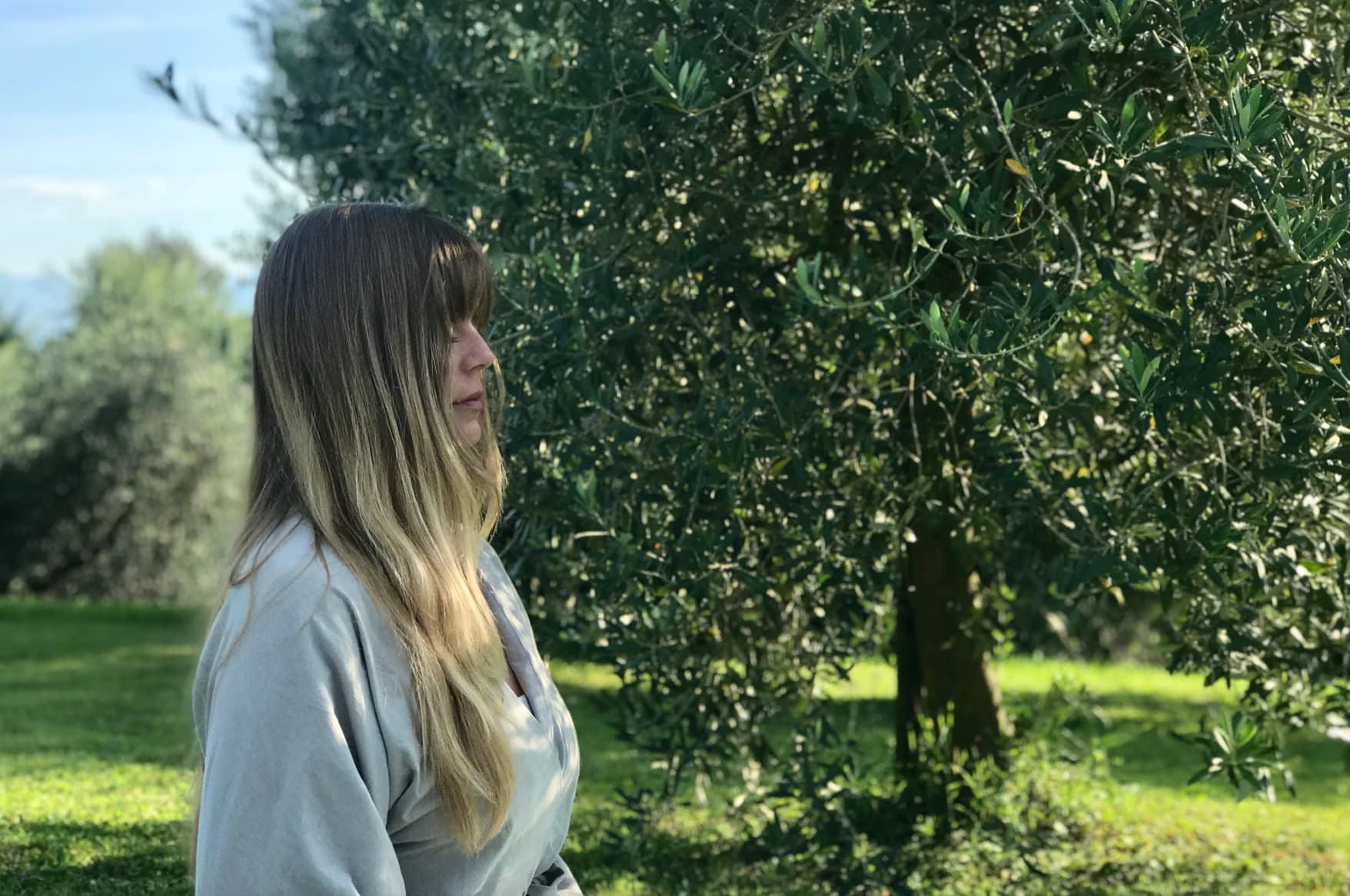 Frau schließt ihre Augen und meditiert unter einem Baum