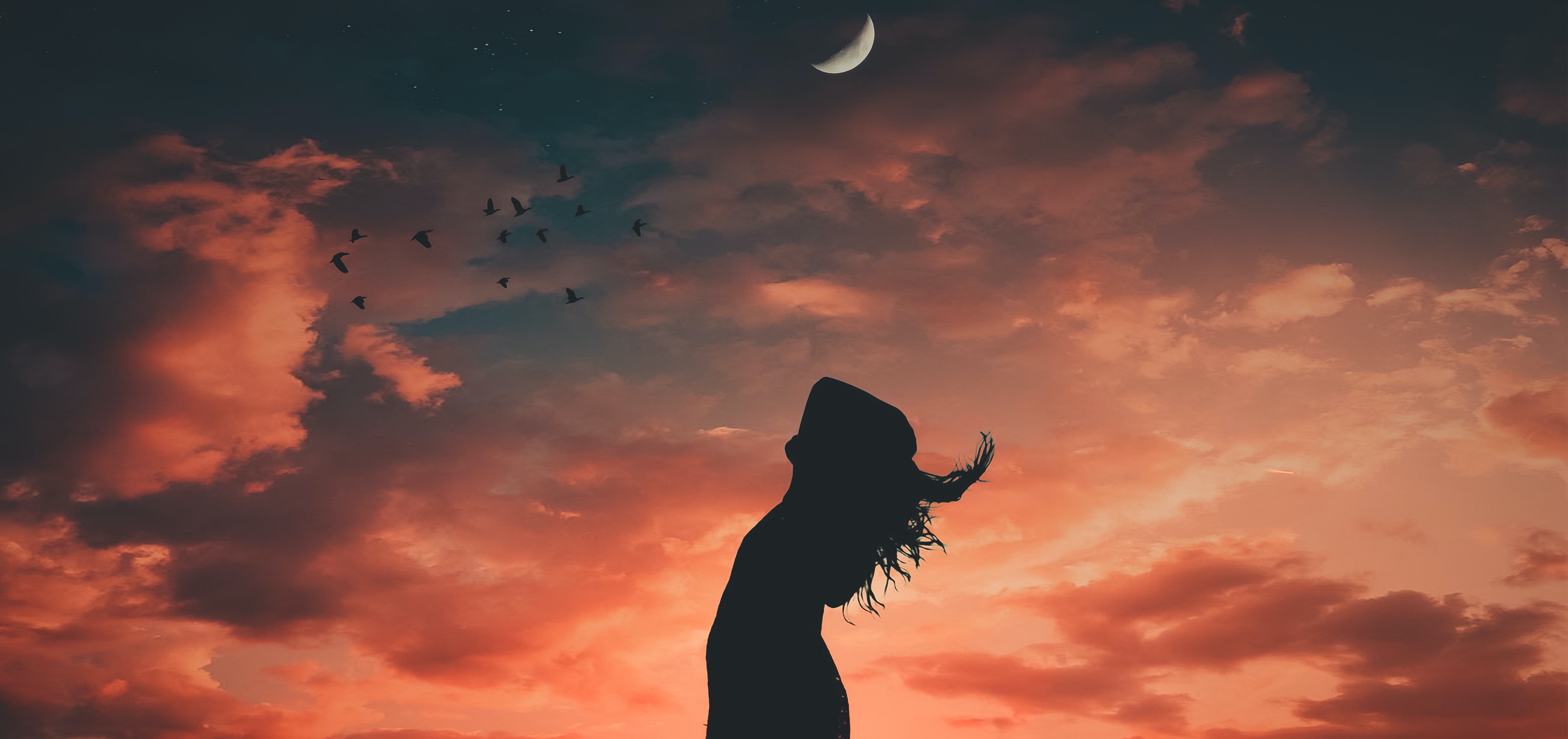 Eine Frau mit weit geöffneten Armen und Blick zum Himmel
